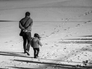 Parent and child walking in the sand.