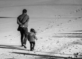 Parent and child walking in the sand.