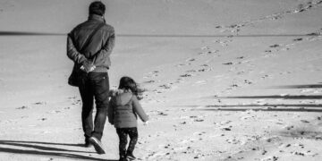 Parent and child walking in the sand.