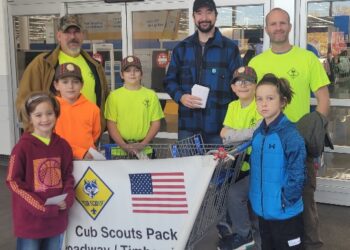 Boy scouts standing with parents for a food drive.