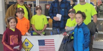 Boy scouts standing with parents for a food drive.