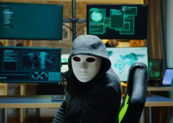 masked hacker at computers.