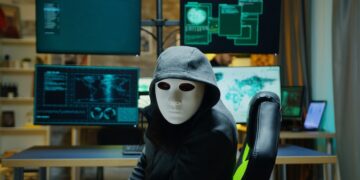 masked hacker at computers.