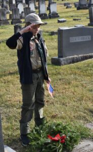 Boy scout saluting at grave.
