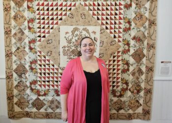 Woman standing in front of a quilt.