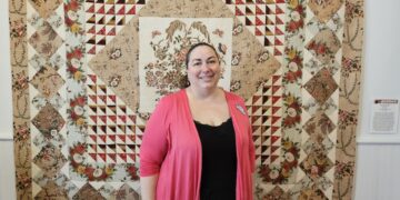 Woman standing in front of a quilt.